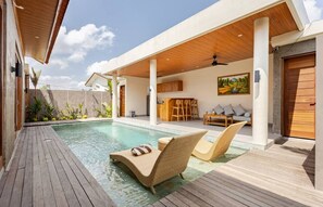Een modern buitenzwembad met ligbedden en een houten terras.