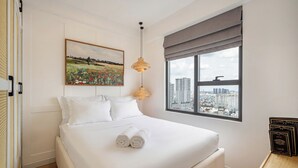 A hotel room with a large bed, a city view, a painting on the wall, and a wooden side table. - The Heart of Saigon Soho Central (Ho Chi Minh City)