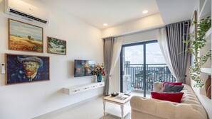 A modern living room with a large window, a sofa, and artwork on the walls. - The Heart of Saigon Soho Central (Ho Chi Minh City)