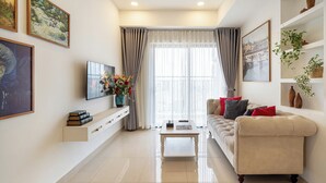 A modern living room with a sofa, coffee table, TV, and artwork on the walls. - The Heart of Saigon Soho Central (Ho Chi Minh City)