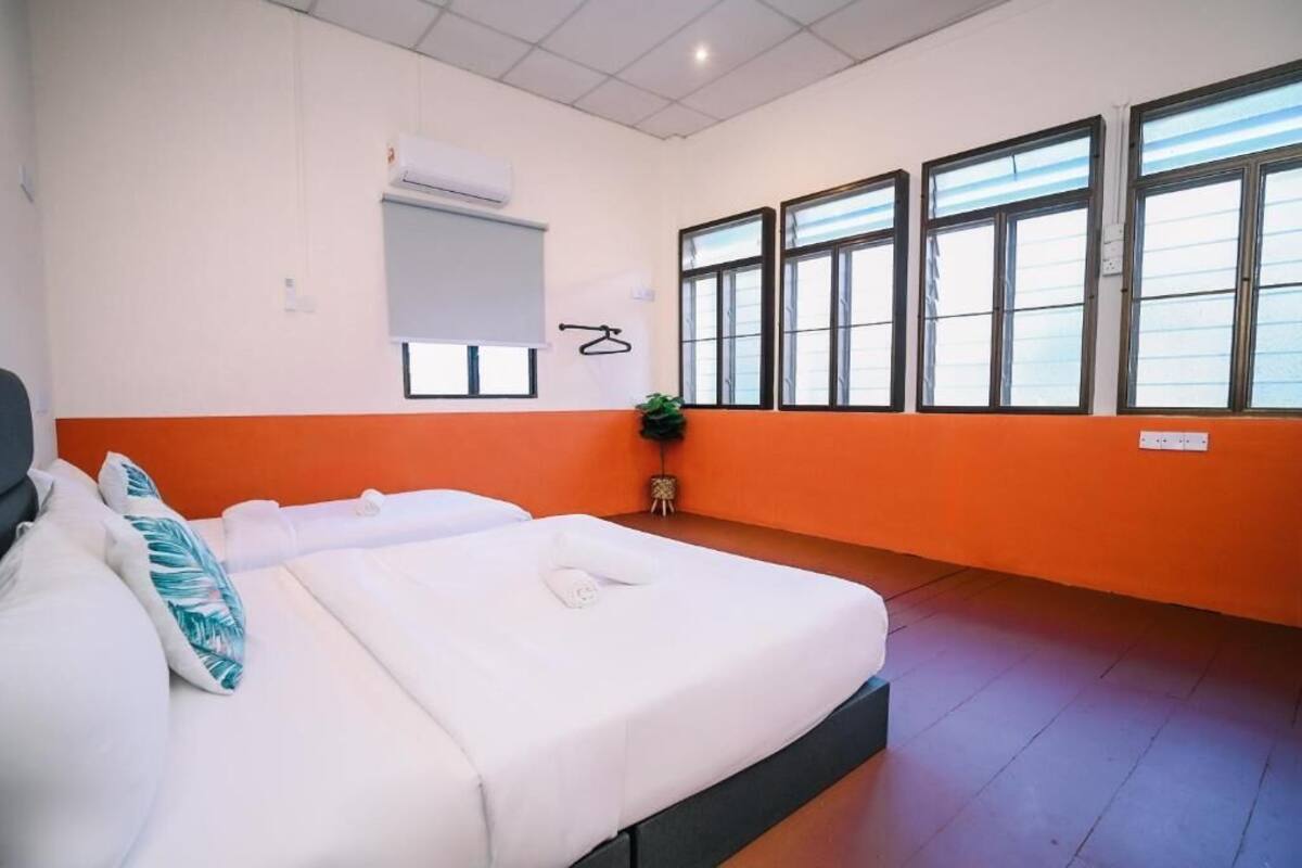 Ein Hotelzimmer mit zwei Betten, einer Klimaanlage, einem Fenster mit Jalousien und einer Pflanze.