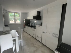 A modern kitchen with white cabinets, a black countertop, and a window providing natural light.