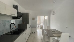 Une cuisine moderne avec des meubles blancs, un robinet noir et un coin repas comprenant une table et des chaises.