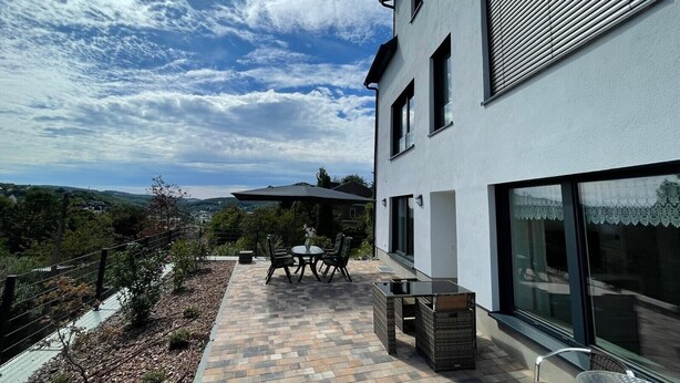 Une maison moderne dotée d’un patio, de mobilier d’extérieur et offrant une vue panoramique.