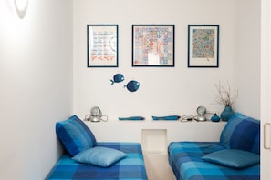 Un dormitorio moderno con dos camas, una estantería decorada y tres obras de arte enmarcadas en la pared.