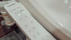Un control remoto CUCKOO con varios botones e iconos, probablemente para un electrodoméstico de baño.