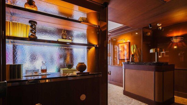 A bar area with a wooden counter, shelves with bottles, and a tiled floor. - Confidential Suite 6, a Stone's Throw From the Louvre (Paris)
