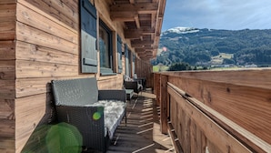 A wooden balcony with wicker furniture and a view of a mountainous landscape. - Apartment at the ski Lift in Jochberg (Jochberg)