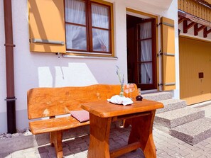 A wooden bench and table set outside a building with a yellow door and windows. - Country house Steibis - Seelekopf (Oberstaufen)