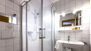 Et moderne badeværelse med en bruseniche, toilet og et vaskebord med et spejl over.