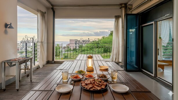 A balcony with a wooden table set for a meal, featuring various dishes and a lantern. - Samcheok Sea Road Pension (Samcheok)