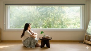 A room with a large window, a small wooden table with a cup and saucer, and a potted plant. - Samcheok Sea Road Pension (Samcheok)