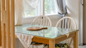 A dining table with two chairs, a glass top, and a wooden coaster. - Samcheok Sea Road Pension (Samcheok)
