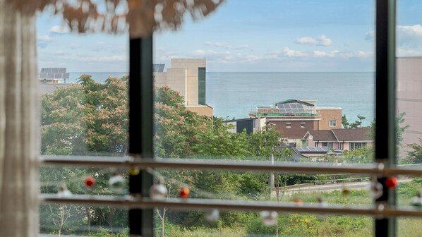A view through a window with a clear view of a coastal area, including buildings and greenery.