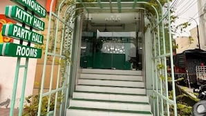 Une entrée d’immeuble avec un escalier menant à un espace abrité, entouré de plantes en pot.