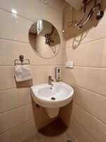 Casa de banho com lavatório branco, espelho redondo e porta-toalhas.
