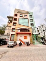 Un edificio de varios pisos con un cartel llamativo de 'Oasis Inn' en la planta baja. Hay dos motocicletas estacionadas y un coche blanco en la parte delantera.