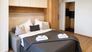 Ett modernt hotellrum med en stor säng, ett inbyggt skrivbord och ett litet kök.