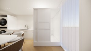 A modern kitchen with a built-in dishwasher, a white sink, and a dining area with a table and chairs.