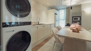 A modern kitchen with a built-in washer and dryer, a microwave, and a dining area with a table and chairs.