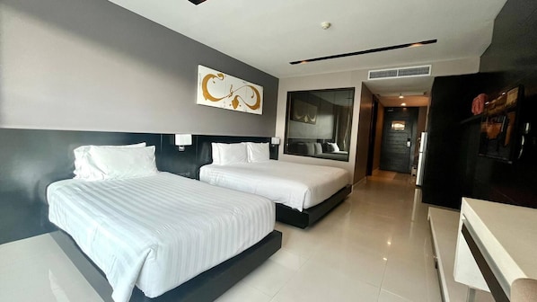 A modern hotel room with two beds, a large mirror, and a dining area. - Studio Apartments With Shared Pool Near Patong Beach (Patong)
