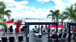 A deck with outdoor seating and umbrellas, overlooking a body of water. - Studio Apartments With Shared Pool Near Patong Beach (Patong)