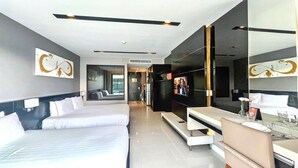 A modern hotel room with a large bed, a TV, a desk, and a seating area. - Studio Apartments With Shared Pool Near Patong Beach (Patong)
