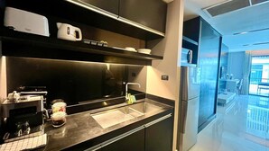 A modern kitchen with a built-in stove, a sink, and a refrigerator. - Studio Apartments With Shared Pool Near Patong Beach (Patong)