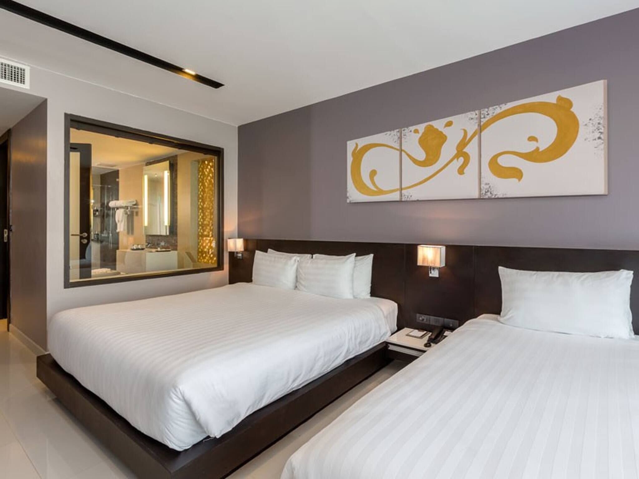 Een hotelkamer met twee bedden, een grote spiegel en een decoratief wandobject.