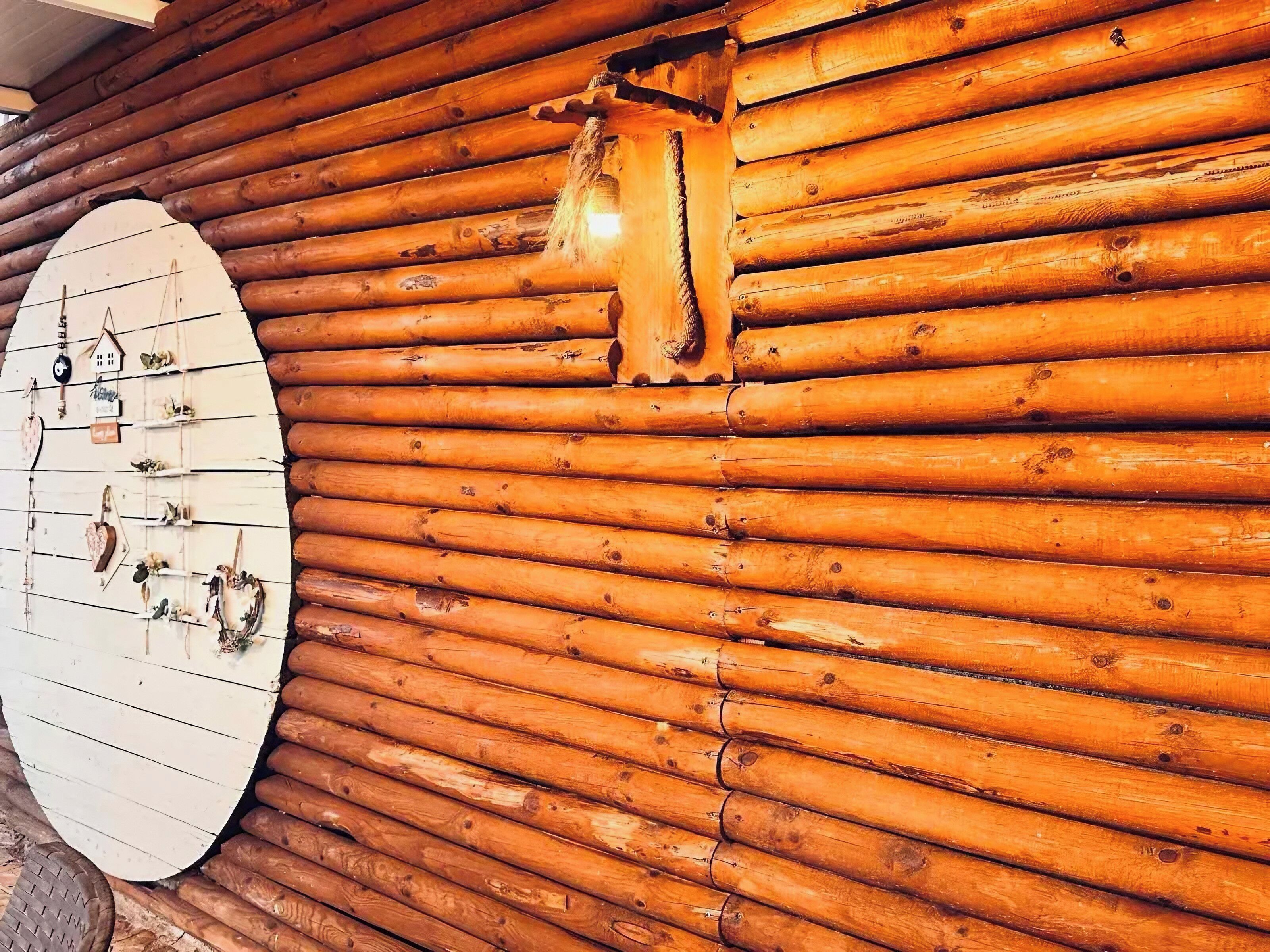 A wooden wall with a large white circular object, possibly a clock or decorative piece, and a small, partially visible door or window.