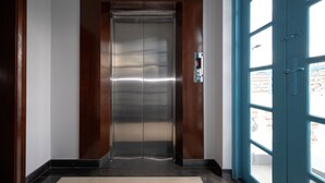 An elevator with a metallic finish, a control panel, and a blue door with glass panels. - The Elegant Comfort Corner in Central District 7, Ho Chi Minh City (P. Tan Phong, Q. 7)