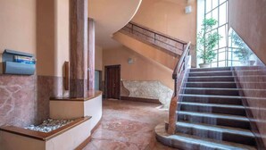 Eine geräumige Lobby mit Marmorboden, einer gewölbten Wand und einer Treppe, die in eine obere Ebene führt.