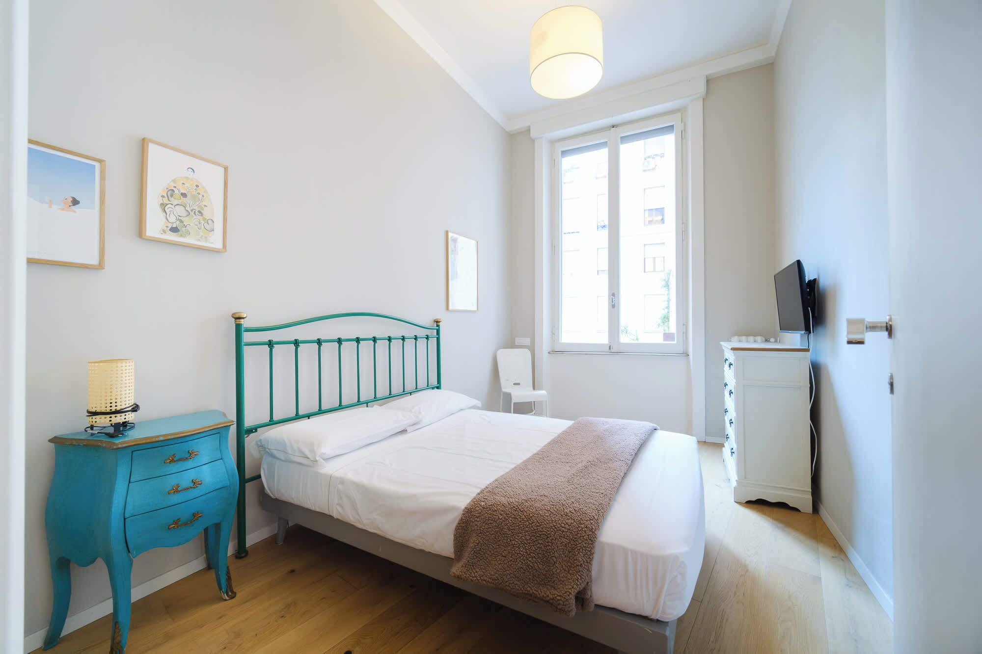 Un dormitorio con cama, mesita de noche, silla, cómoda y ventana.