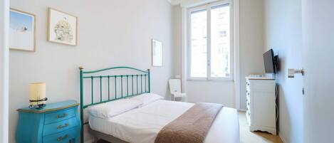 Un dormitorio con cama, mesita de noche, silla, cómoda y ventana.