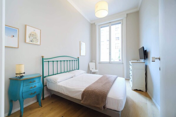 A bedroom with a bed, a nightstand, a chair, a dresser, and a window.