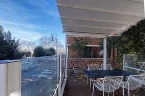 Ein Balkon mit Tisch und Stühlen, einem Blumentopf und Blick auf geparkte Autos.