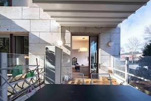A modern building with a balcony, a glass door leading to an interior space, and a view of the outside.