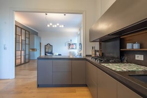 A modern kitchen with a central island, a built-in stove, and a large window.