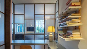 Ein moderner Büroraum mit Schreibtisch, Stuhl, Lampe und einem Bücherregal voller Bücher.