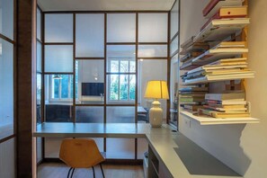 Een moderne kantoorruimte met een bureau, stoel, lamp en een boekenplank vol boeken.