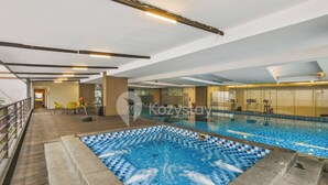 Ein Hallenbad mit gefliestem Boden und einem separaten Whirlpoolbereich.