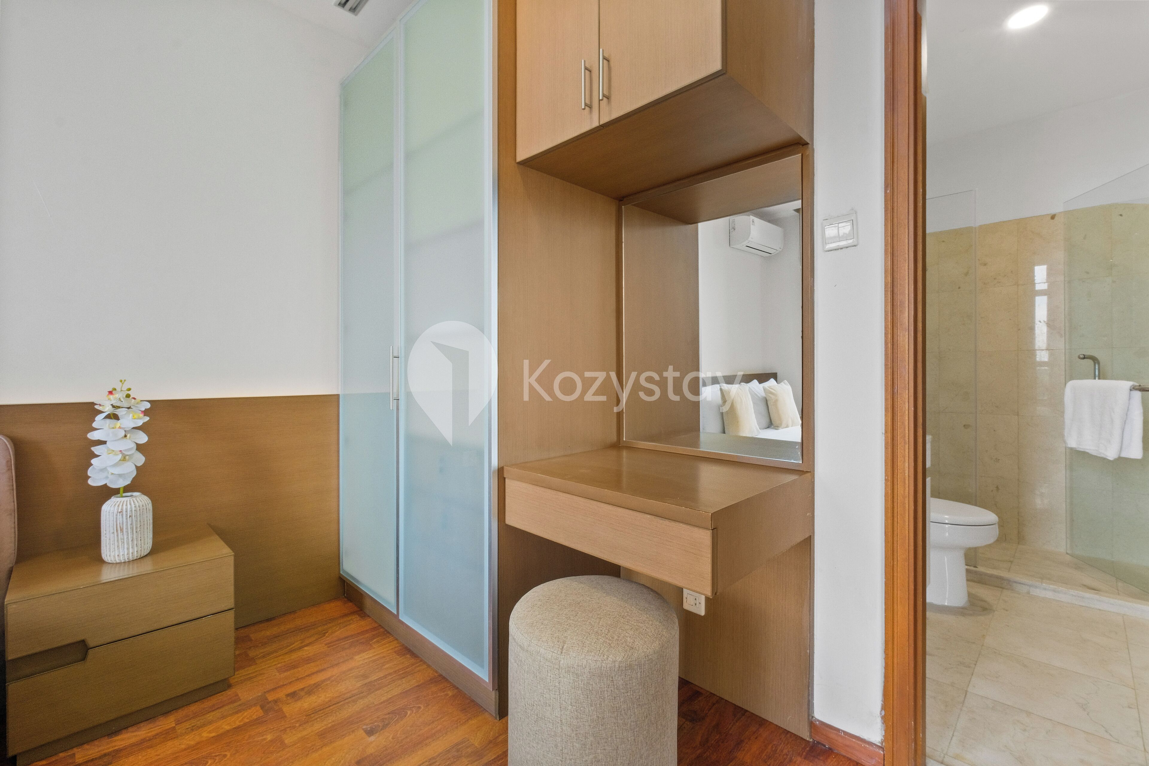A modern bathroom with a wooden vanity, a mirror, a toilet, and a shower area.