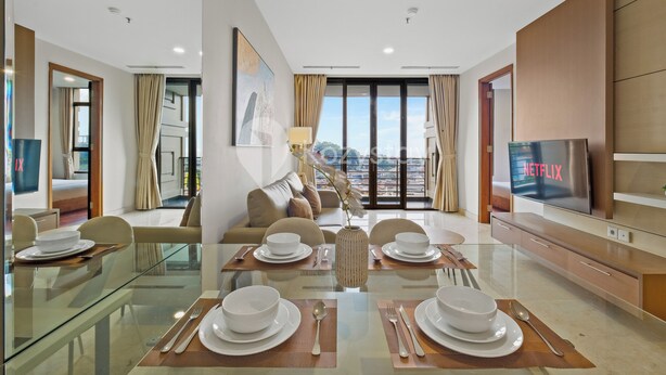Ein modernes Hotelzimmer mit Essbereich, einer Sitzecke, einem Fernseher und Blick auf die Stadt.