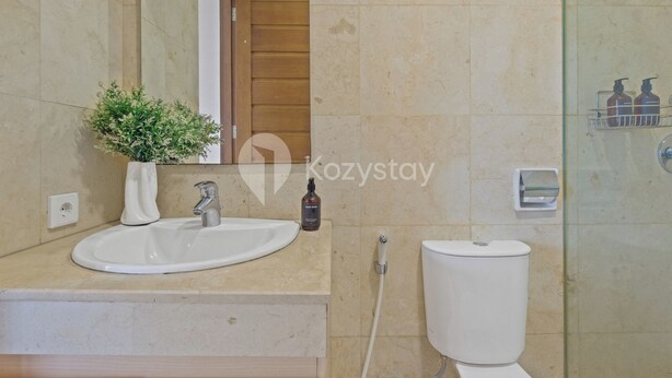 Ein Badezimmer mit Waschbecken, Spiegel, Toilette und Duschbereich.