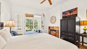 Un dormitorio con cama, chimenea, ventilador de techo, reloj y una pintura.