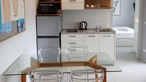 A modern kitchen with white cabinets, a glass dining table, and clear chairs. - 2BR Apartment  T2-717 (Chalong)