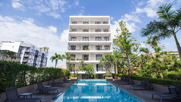 A modern multi-story building with a swimming pool and lounge chairs. - 2BR Apartment  T2-717 (Chalong)