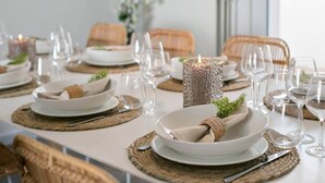 A dining table set with white plates, clear glasses, and woven placemats. - Spacious townhouse in the centre of Knokke (Knokke-Heist)