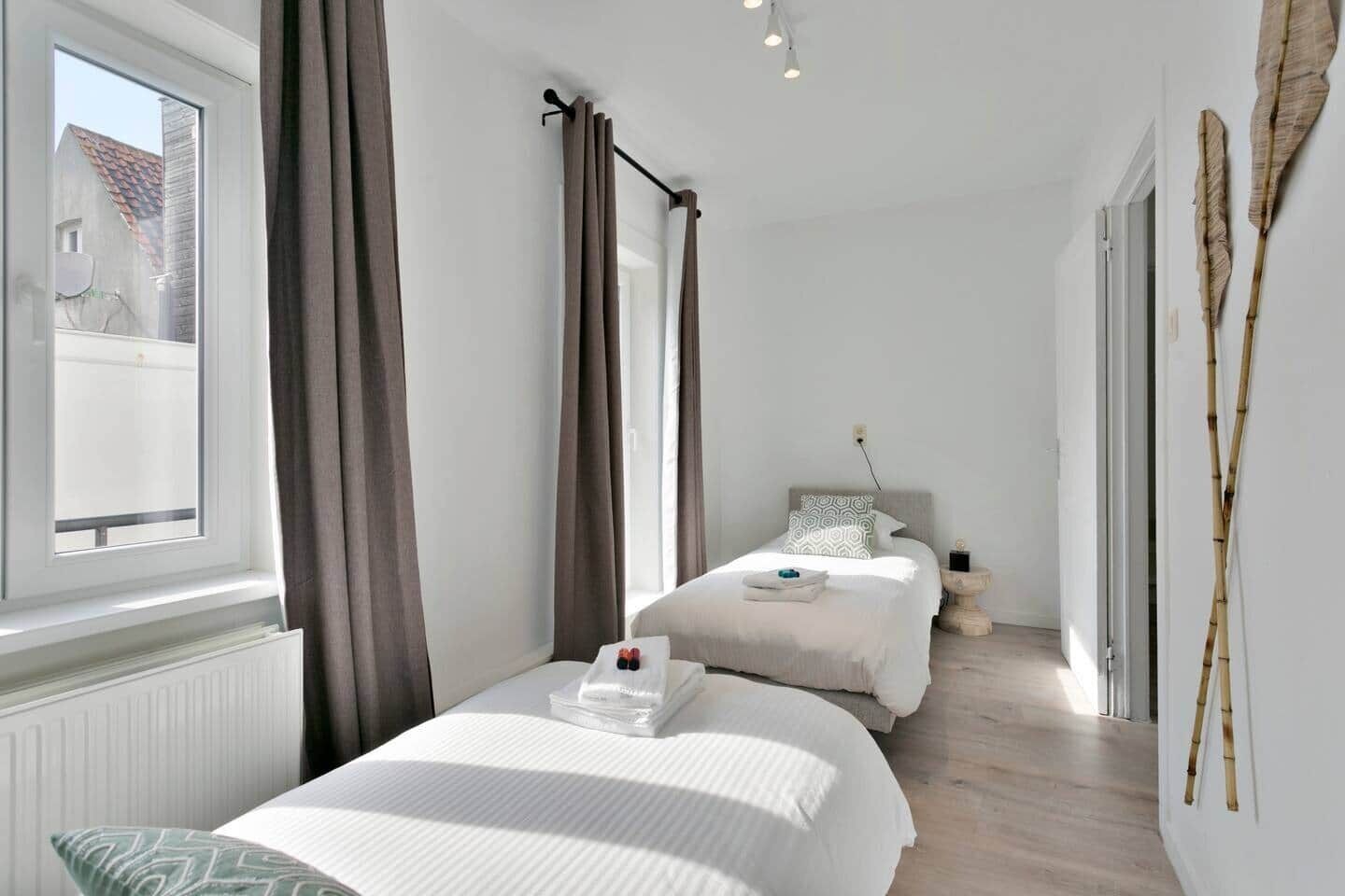A bedroom with two beds, a window, and a view of the outside.