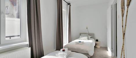 A bedroom with two beds, a window, and a view of the outside.
